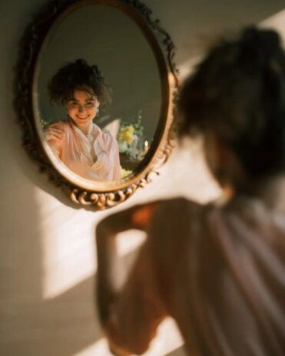 Mujer frente al espejo sonriéndose a si misma
