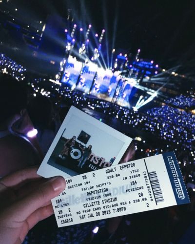 Asistente sostiene boleto de concierto frente a escenario iluminado durante festival Tecate Emblema en la CDMX.