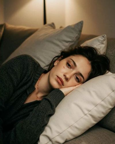 Mujer recostada en un sofá con expresión de cansancio o tristeza, posible señal de depresión perinatal o trastornos hormonales.