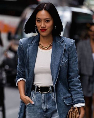Mujer con mezclilla azul combinado con top blanco y jeans, look denim sobre denim con cinturón negro y collar dorado.