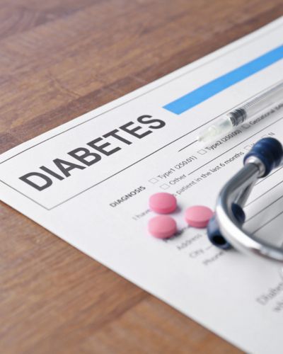Hoja con la palabra “DIABETES” junto a un estetoscopio, glucómetro y pastillas.