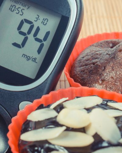 Glucómetro marcando 94 mg/dL junto a postres en moldes de silicón.