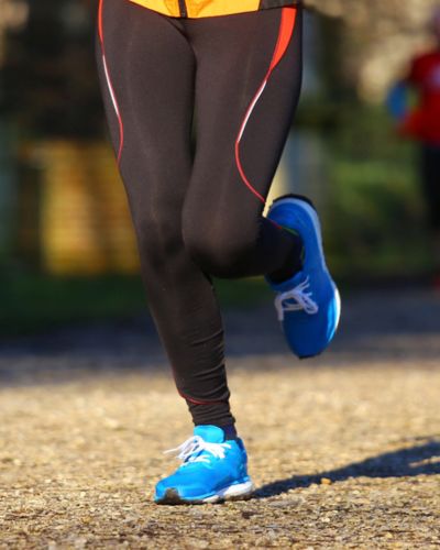 Piernas de una persona corriendo al aire libre con tenis deportivos azules.