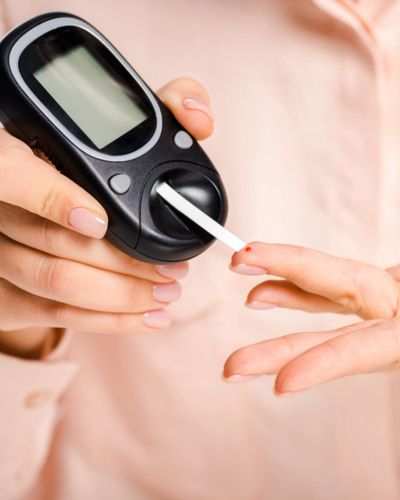 Persona realiza una prueba de glucosa con glucómetro y tira reactiva en el dedo.