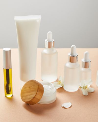 Perfumes y cosméticos sobre una superficie con pétalos y rosas claras, estética romántica.