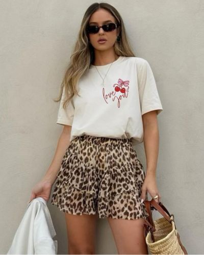 Modelo viste camiseta gráfica en color blanco y short animal print.