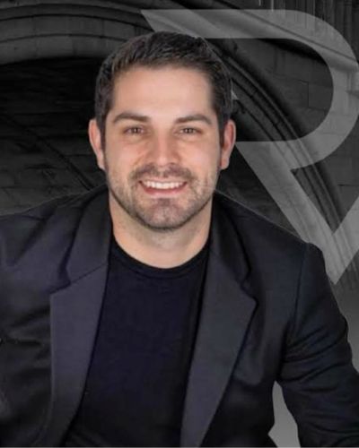Foto del Dr. Rafael Vizcaino con saco negro, sonriendo frente a fondo gris.