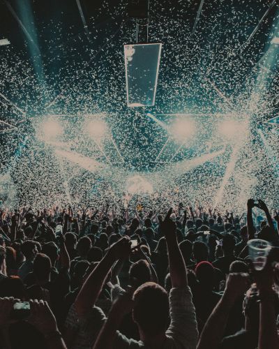 Multitud en un concierto con confeti cayendo y luces potentes de escenario, ambiente típico de festival como Corona Capital 2026.