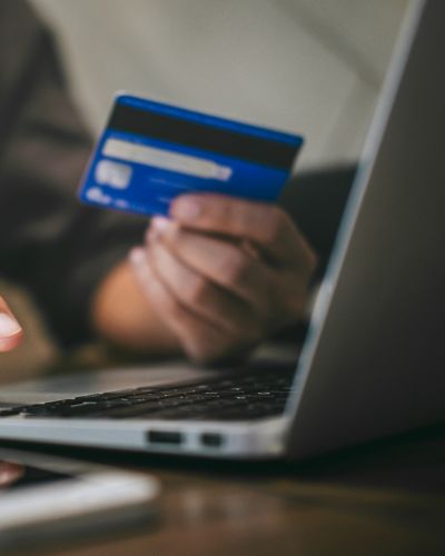 Persona usando una laptop mientras sostiene una tarjeta bancaria, representando la compra en línea de boletos Corona Capital.