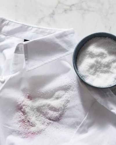 Foto muestra cómo espolvorear bicarbonato de sódio puede ayudar a quitar manchas de vino tinto sobre la ropa.