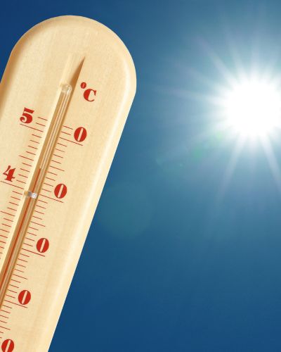 Termómetro marcando alta temperatura frente a un cielo azul con el sol brillante, relacionado con el debate del calendario escolar por el Mundial 2026 y las vacaciones de verano.