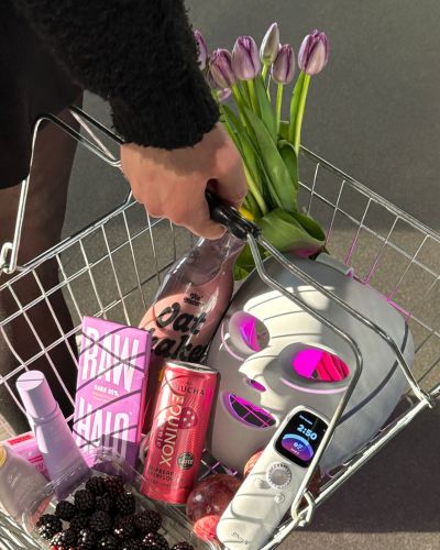 Carrito de compras con tulipanes, productos de belleza y un dispositivo de cuidado facial, ideas variadas de regalos para mamá.