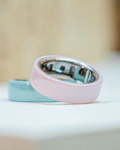 Dispositivo portátil tipo anillo en tonos pastel sobre una superficie blanca, opción de gadget para bienestar como regalo del 10 de mayo.