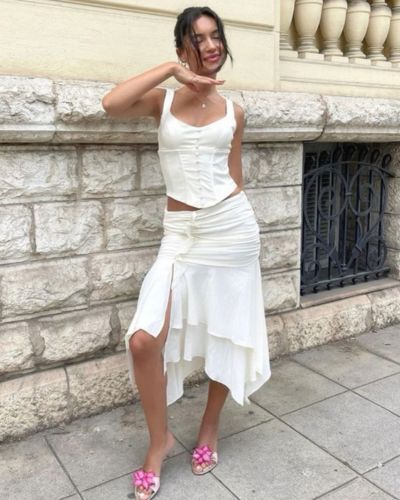 Outfit con pieza con volumen en la parte inferior y prenda ceñida en la parte superior, con sandalias mule rosadas 