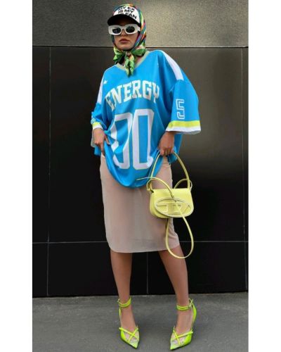 Look sporty chic con camiseta oversized azul, falda sastre de corte midi en color beige y stilettos neón.