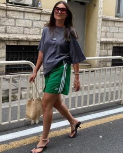 Look sporty chic con bermudas deportivas color verde y camiseta gris oversized y sandalias mule