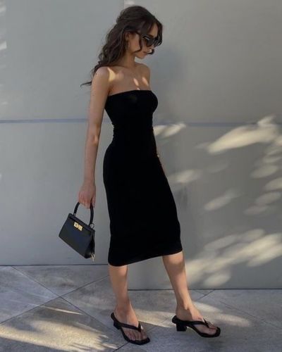 Modelo viste vestido midi negro con sandalias mule 