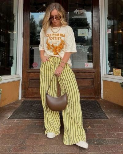 Tendencias cool: pantalones a rayas con t-shirt estampada en color blanco, tenis blancos y bolso estructurado café