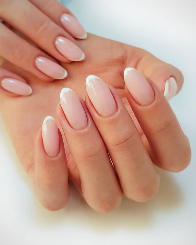 Manos con manicure nude brillante y uñas almendradas, resultado de una rutina para uñas impecables y beneficios en las uñas.