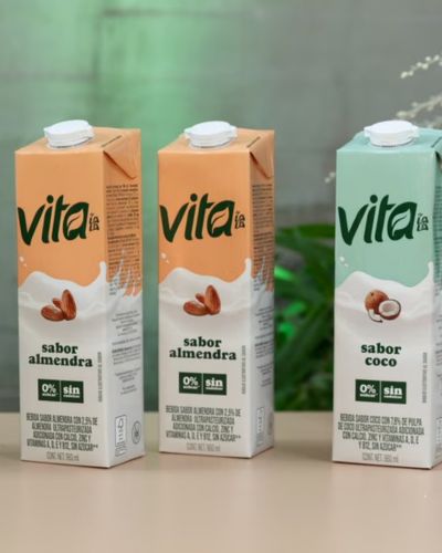 Tres envases de Vita por Lala: dos de bebida de leche vegetal de almendra y uno de coco, colocados sobre una mesa.