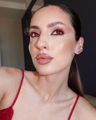 Mujer luciendo un look de rojos y café con una blusa de tirantes en color rojo